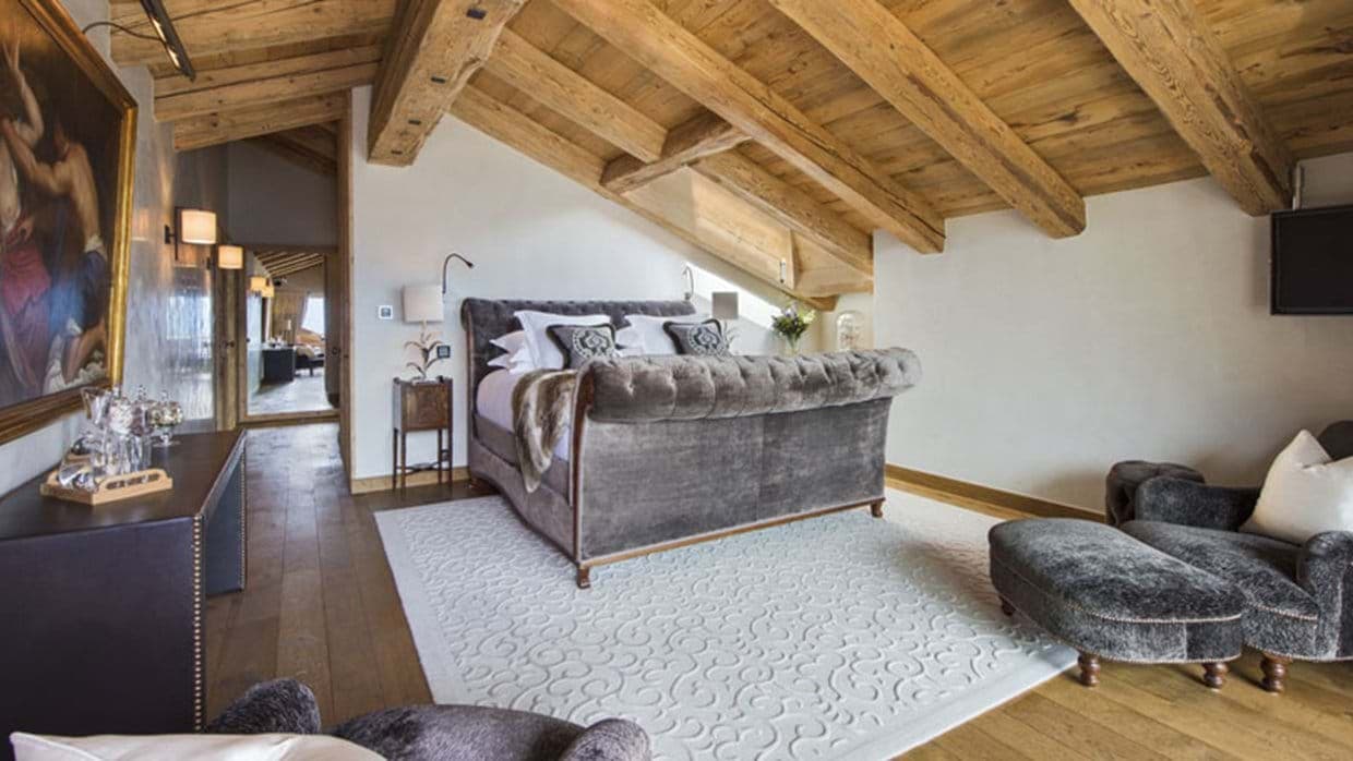 Primary bedroom with tufted king bed and exposed timber beams