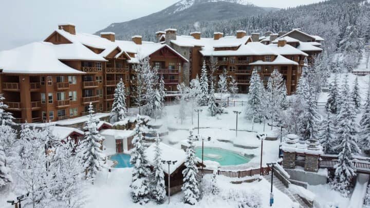 Lodge exterior with heated outdoor pools and mountain backdrop