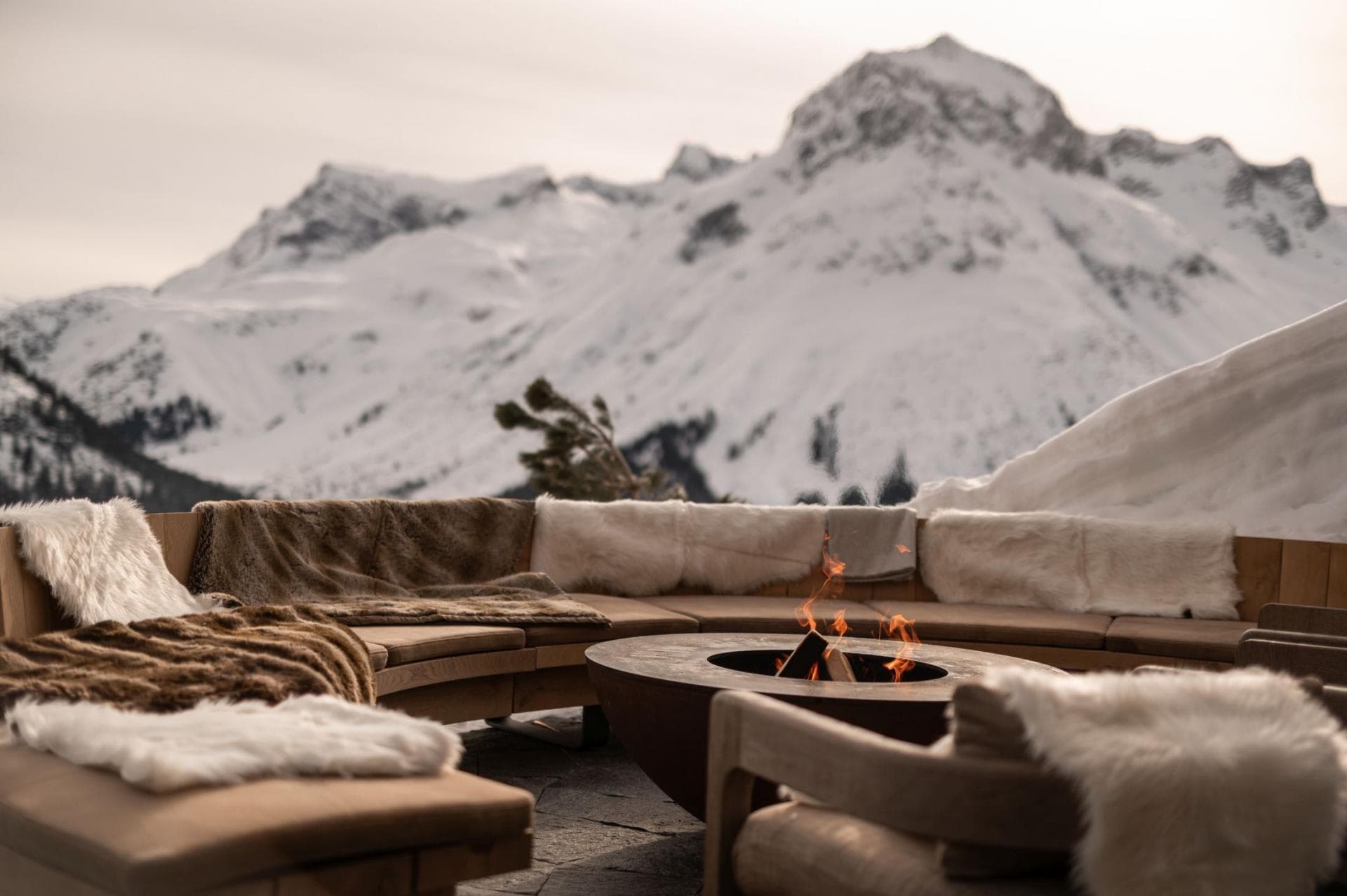 Outdoor wood-burning fire pit with sectional seating and alpine mountain views