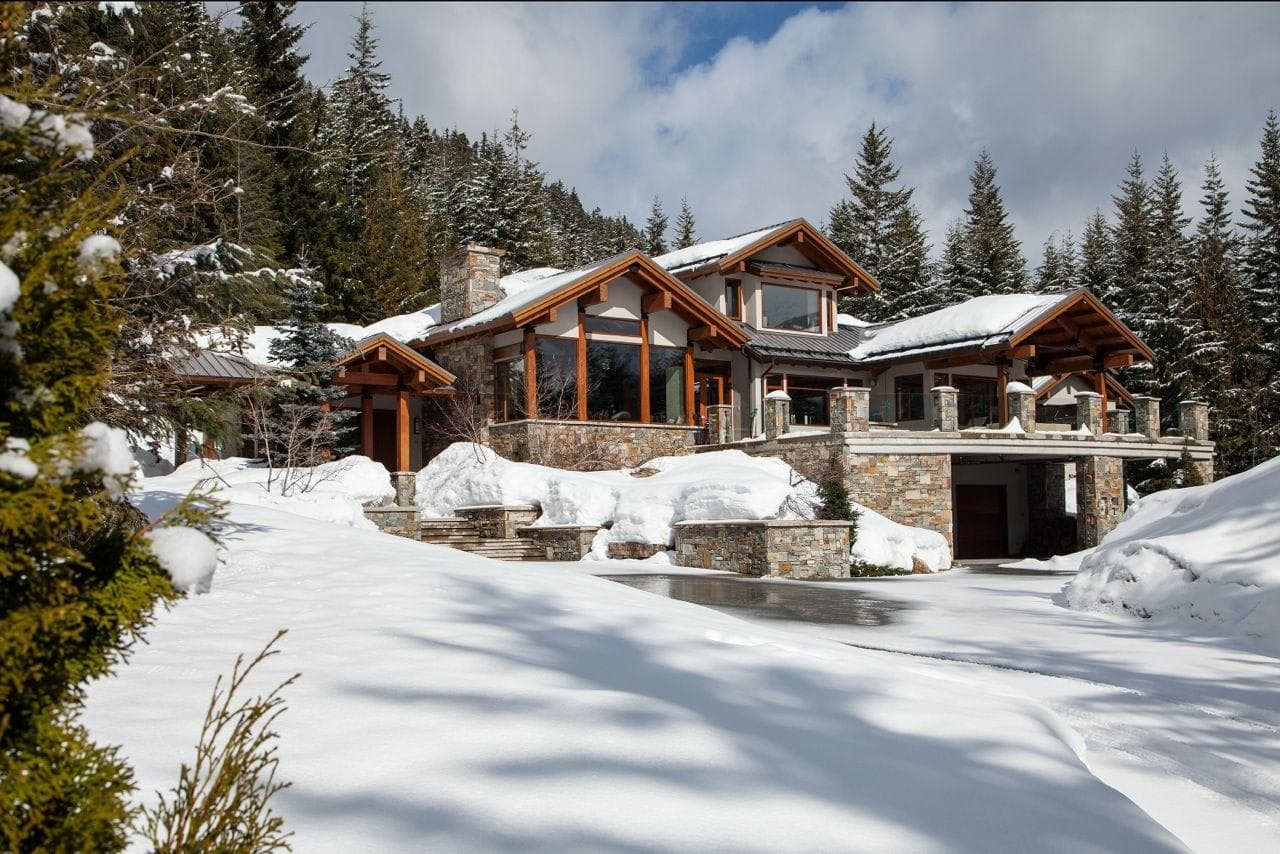 Ski-in chalet with heated driveway, stone exterior, and tiered sun decks