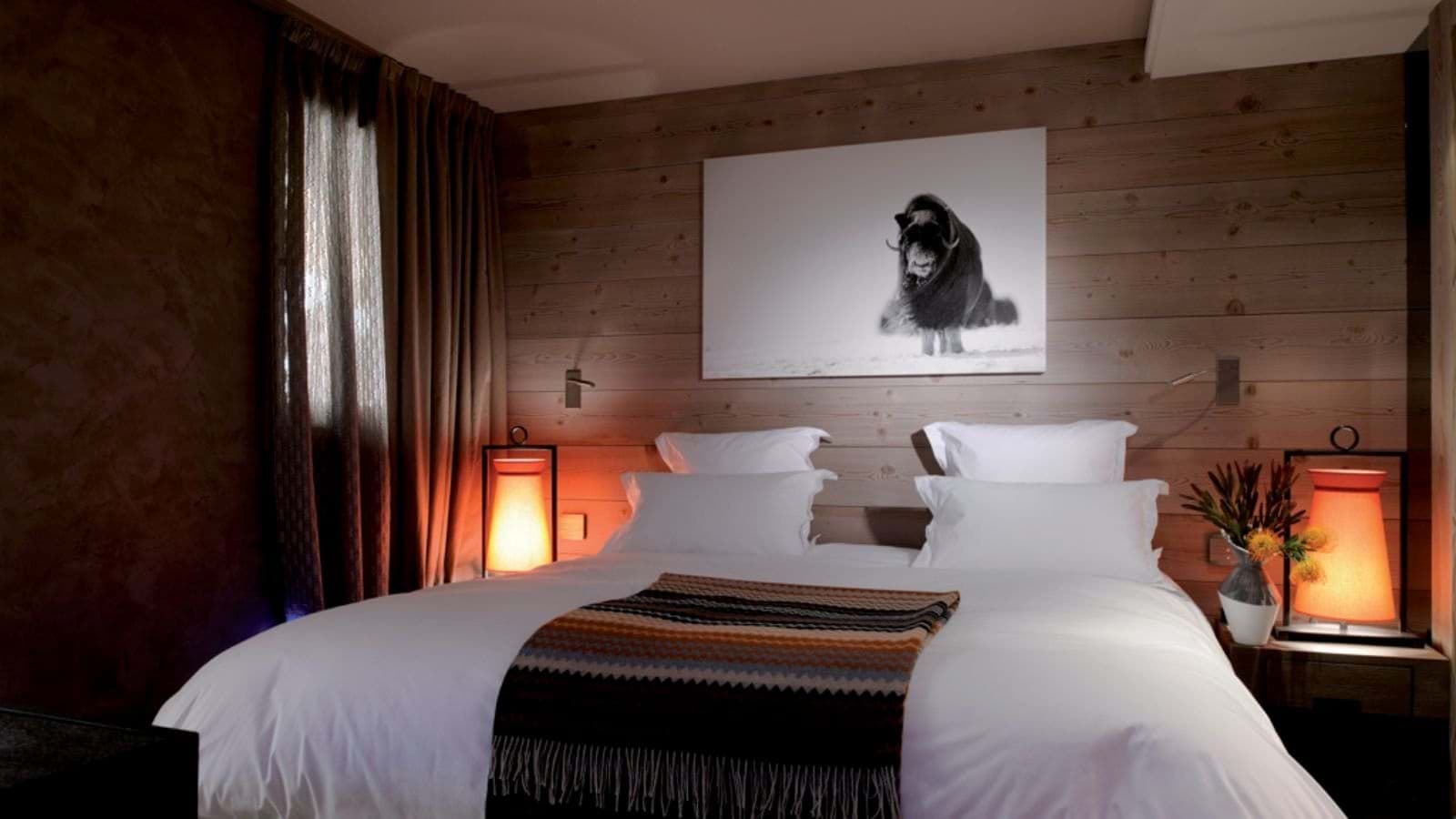 Guest bedroom with king bed, timber-clad walls, and reading lamps