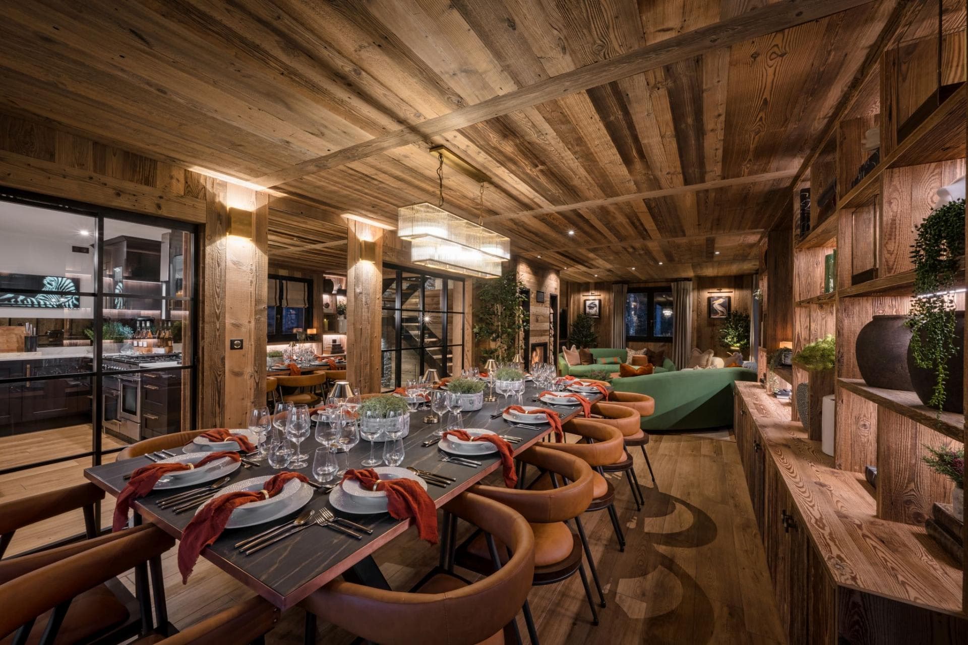 Dining area seating 12 with reclaimed wood paneling and adjacent kitchen