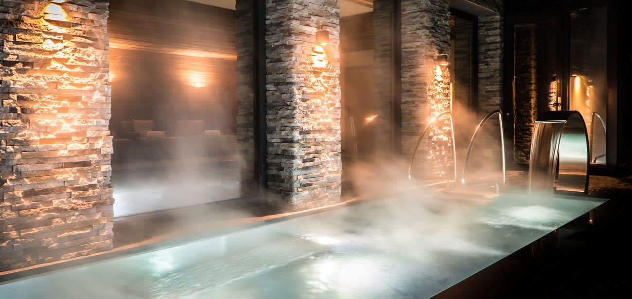 Indoor heated pool with waterfall feature and stacked stone pillars