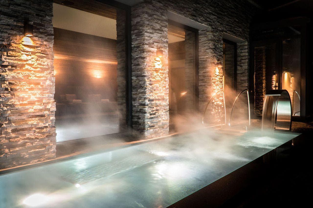 Heated indoor pool with stone walls and waterfall feature