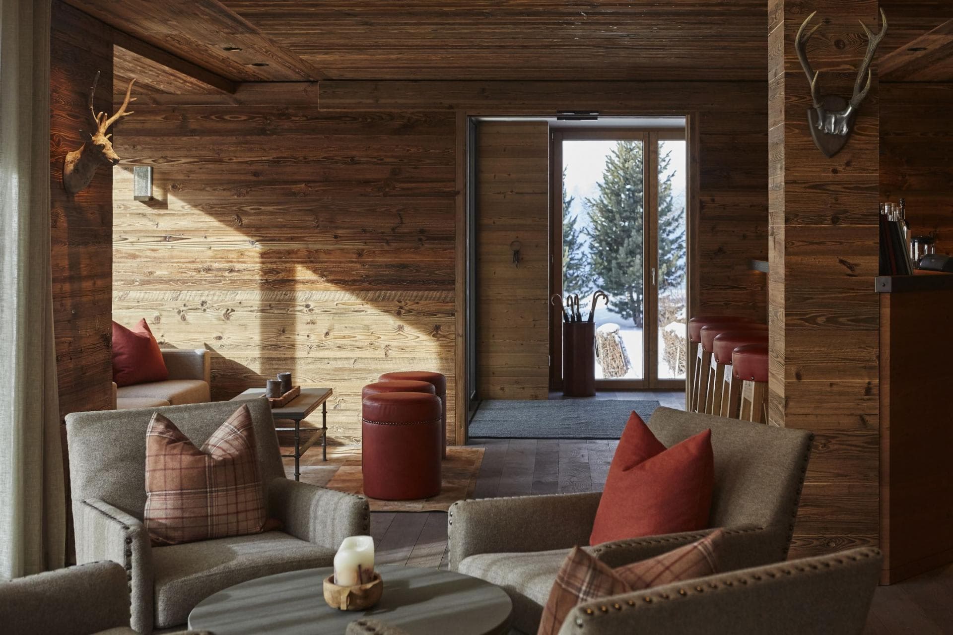 Wood-paneled lounge with bar seating and snowy pine views