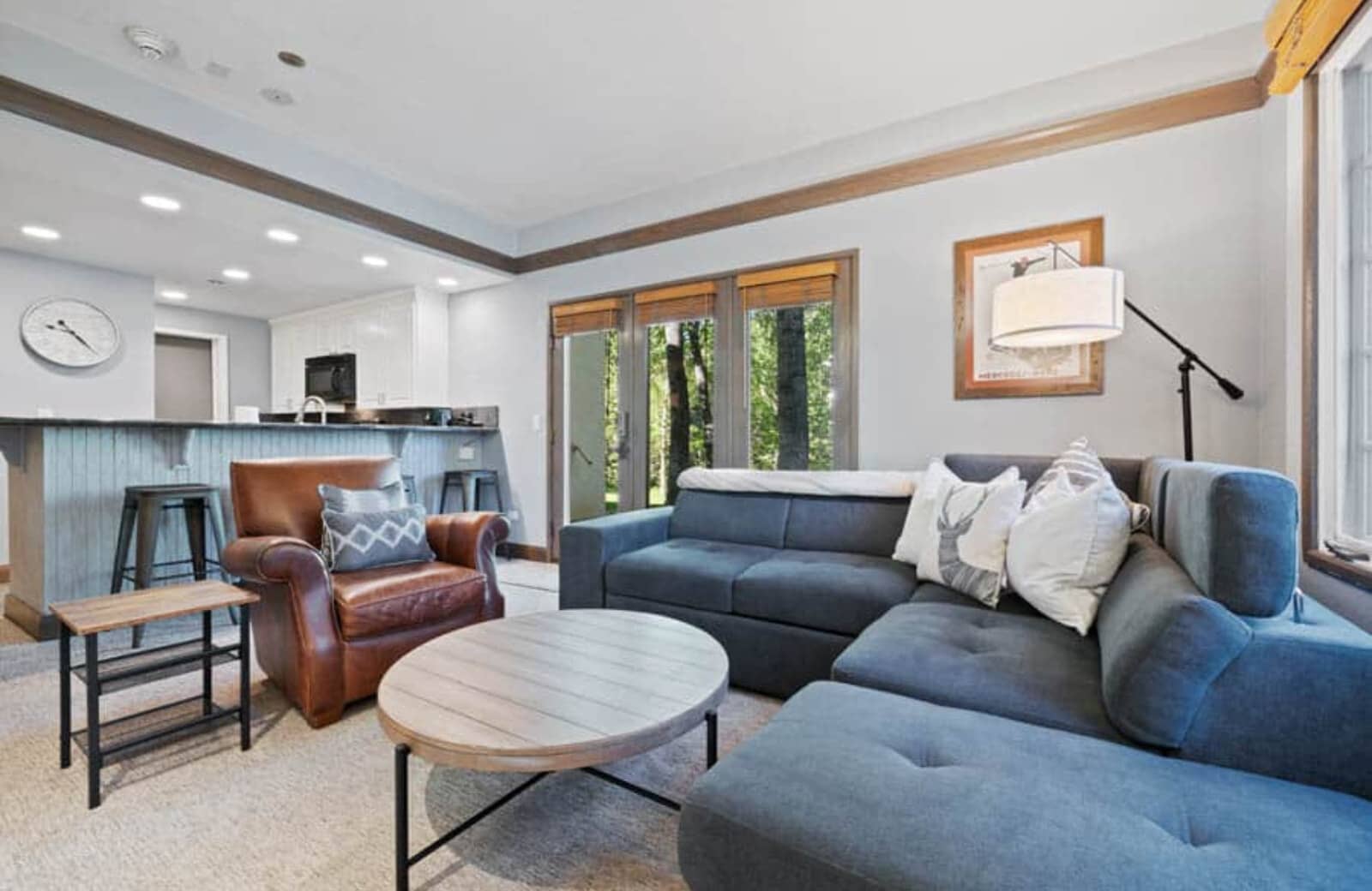Living area with sectional seating and forest views through glass doors
