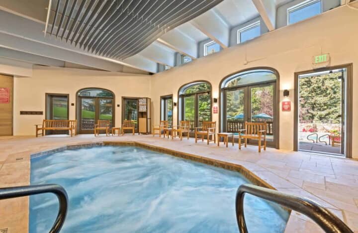 Indoor hot tub with stone tile deck and direct patio access