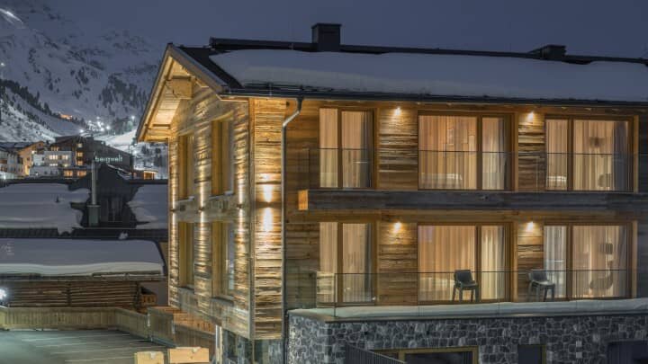 Chalet exterior at night with private glass balconies and village views