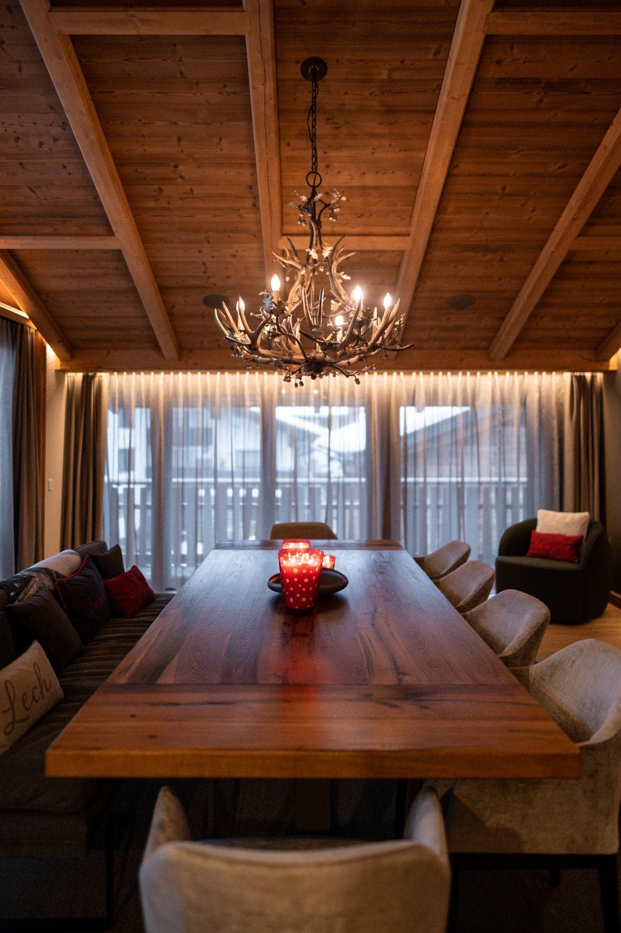 Dining area with antler chandelier, banquet seating, and wood beamed ceiling