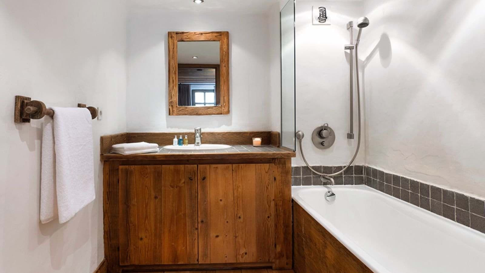 Bathroom with wood vanity and bathtub with handheld shower
