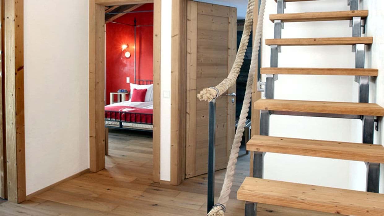 Hallway with wood stairs leading to bedroom with four-poster bed