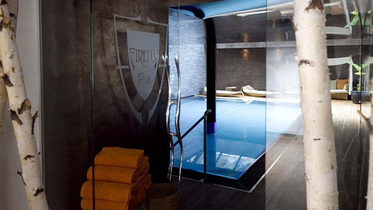 Indoor pool area with glass entry, towel service, and lounge seating