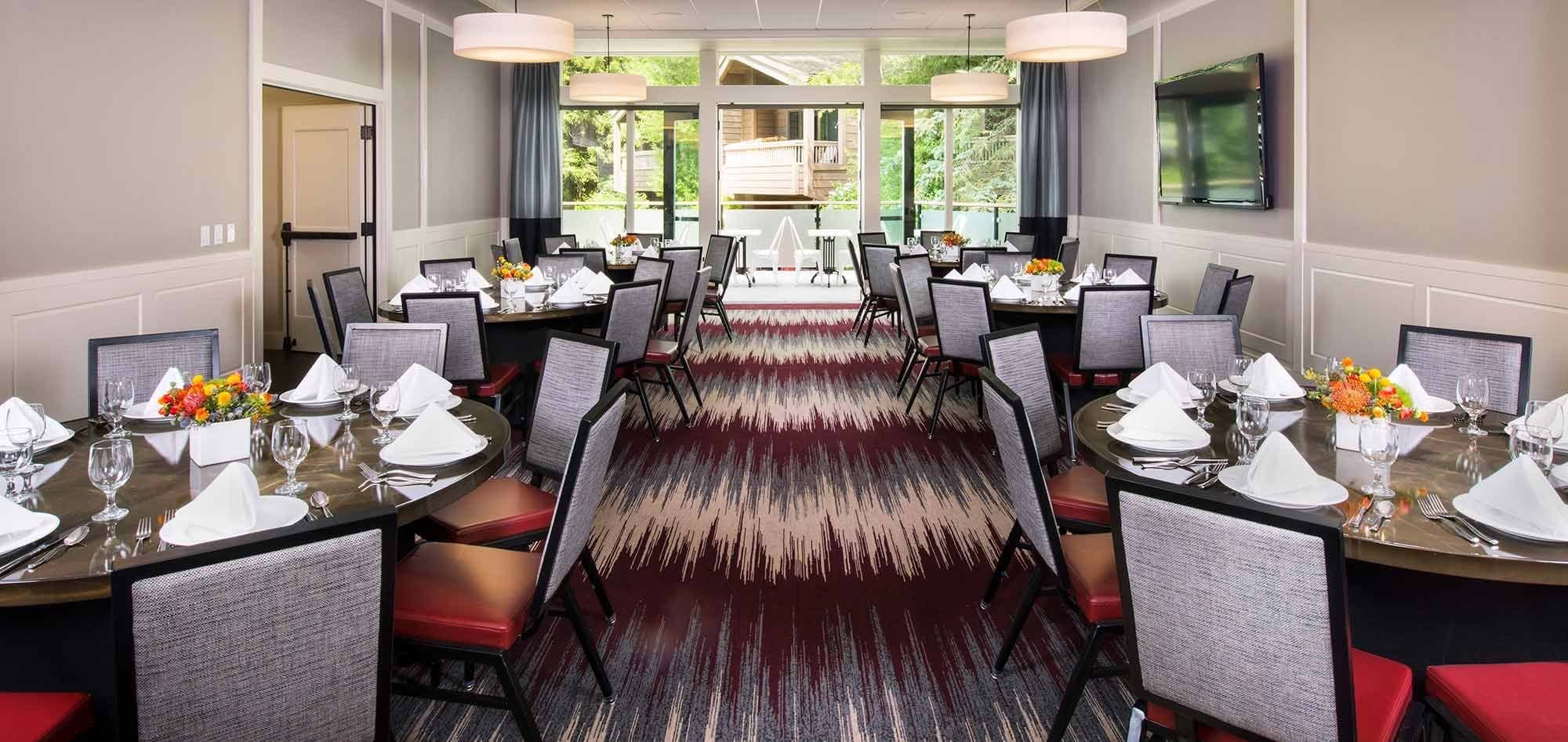 Shared dining area with six round tables and balcony access