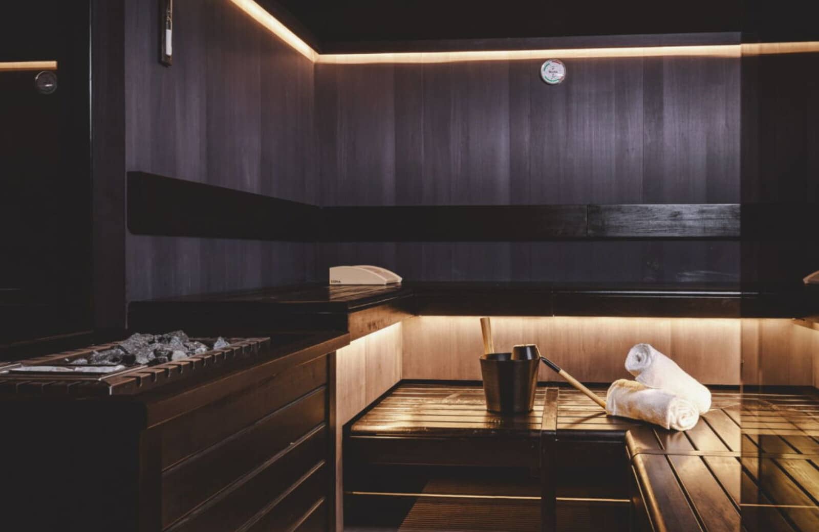 Private sauna with tiered bench seating and traditional rock heater