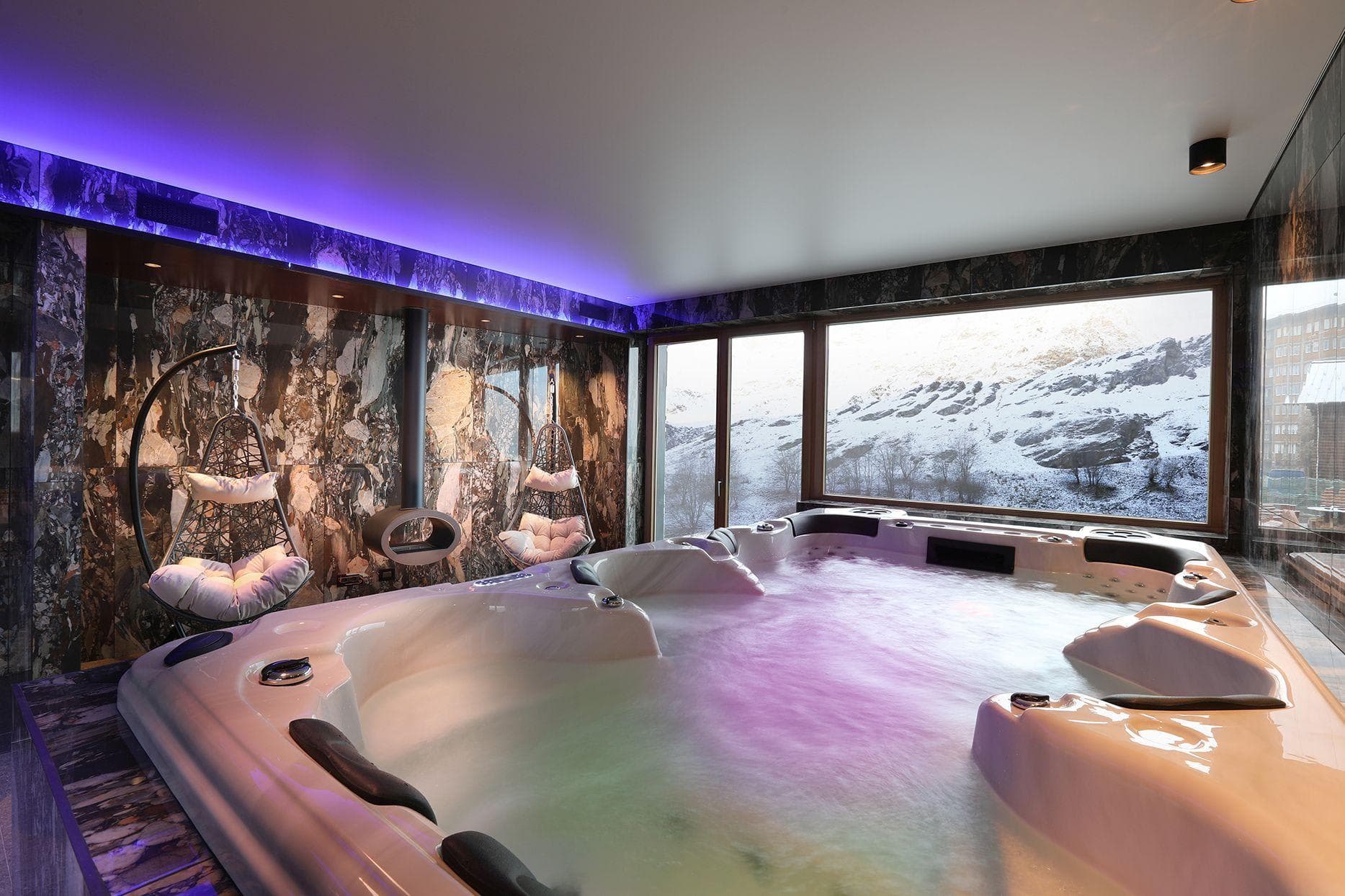 Indoor hot tub and hanging chairs with mountain views