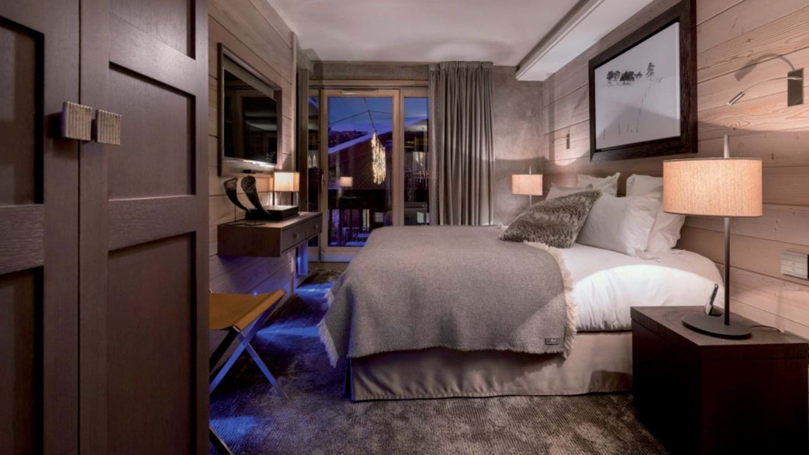 Guest bedroom with queen bed, smart TV, and private balcony access