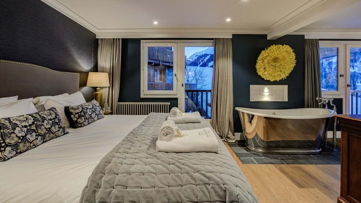 Primary bedroom with king bed and in-room soaking tub; mountain views