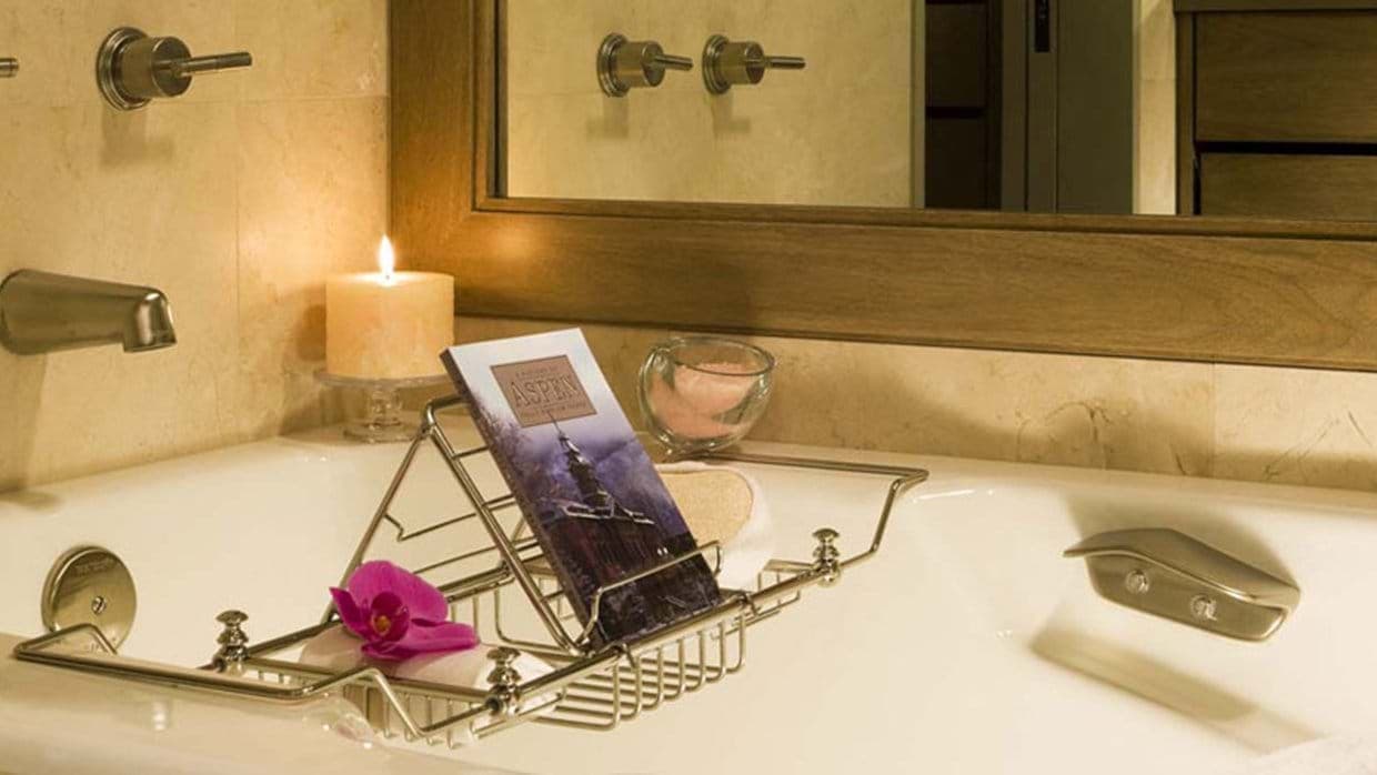 Deep soaking tub with wire caddy and stone tile surround