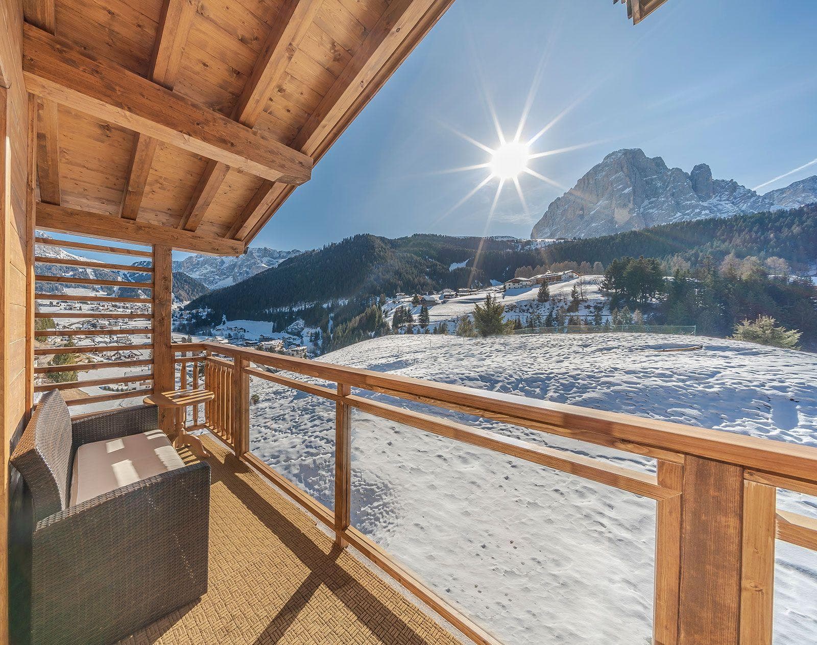 Covered balcony with wicker sofa and glass railings for mountain views