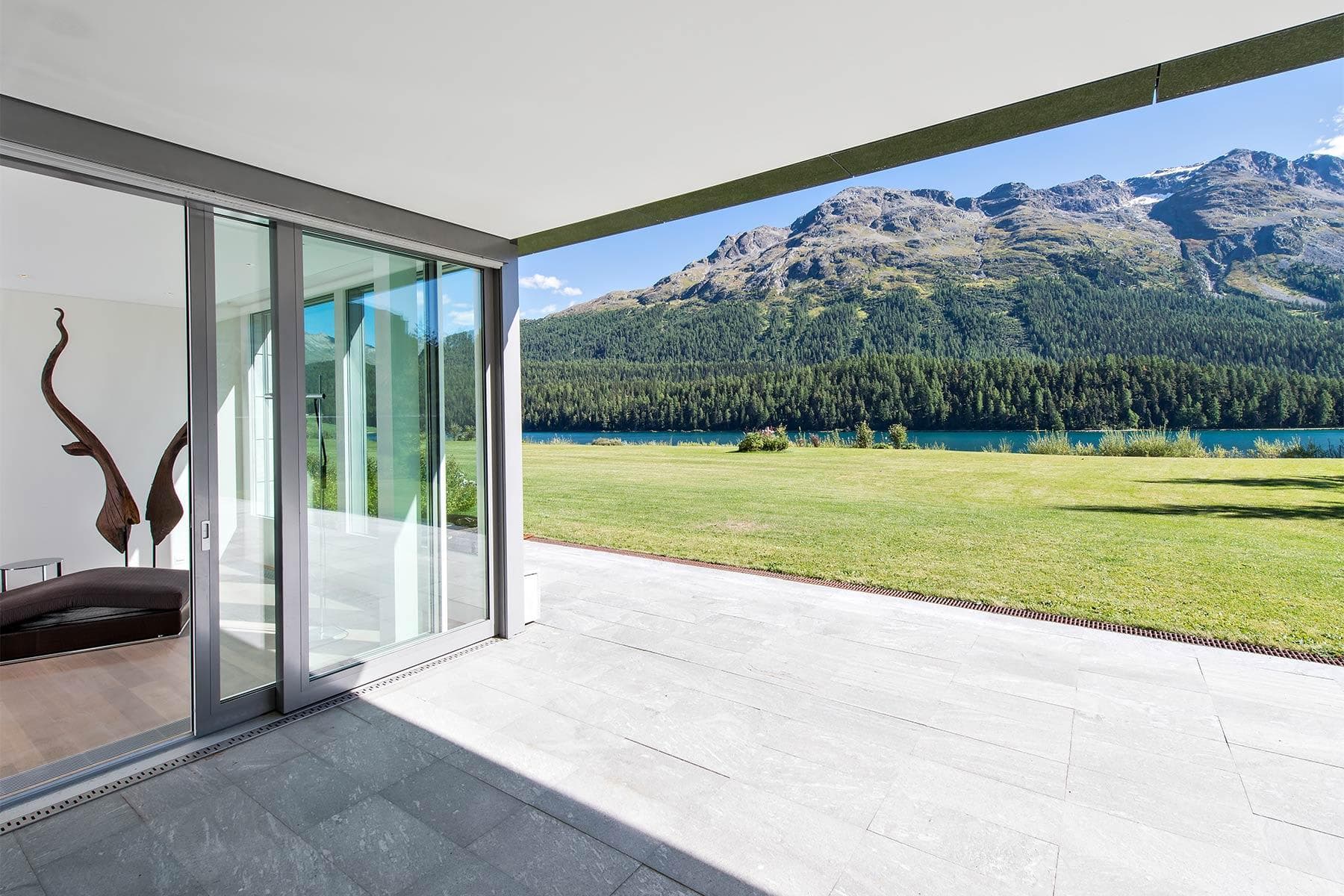 Stone patio with floor-to-ceiling sliding doors; mountain and lake views