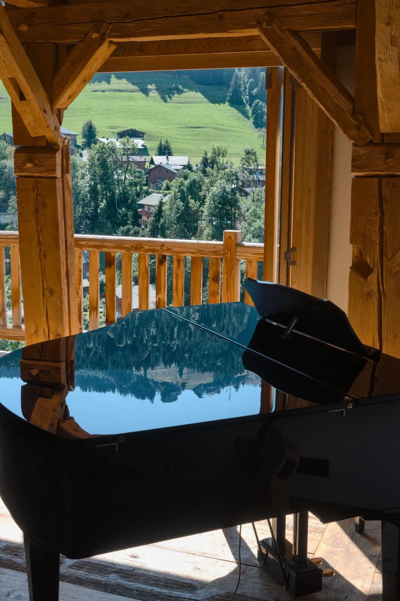 Grand piano in timber-framed room with valley and village views