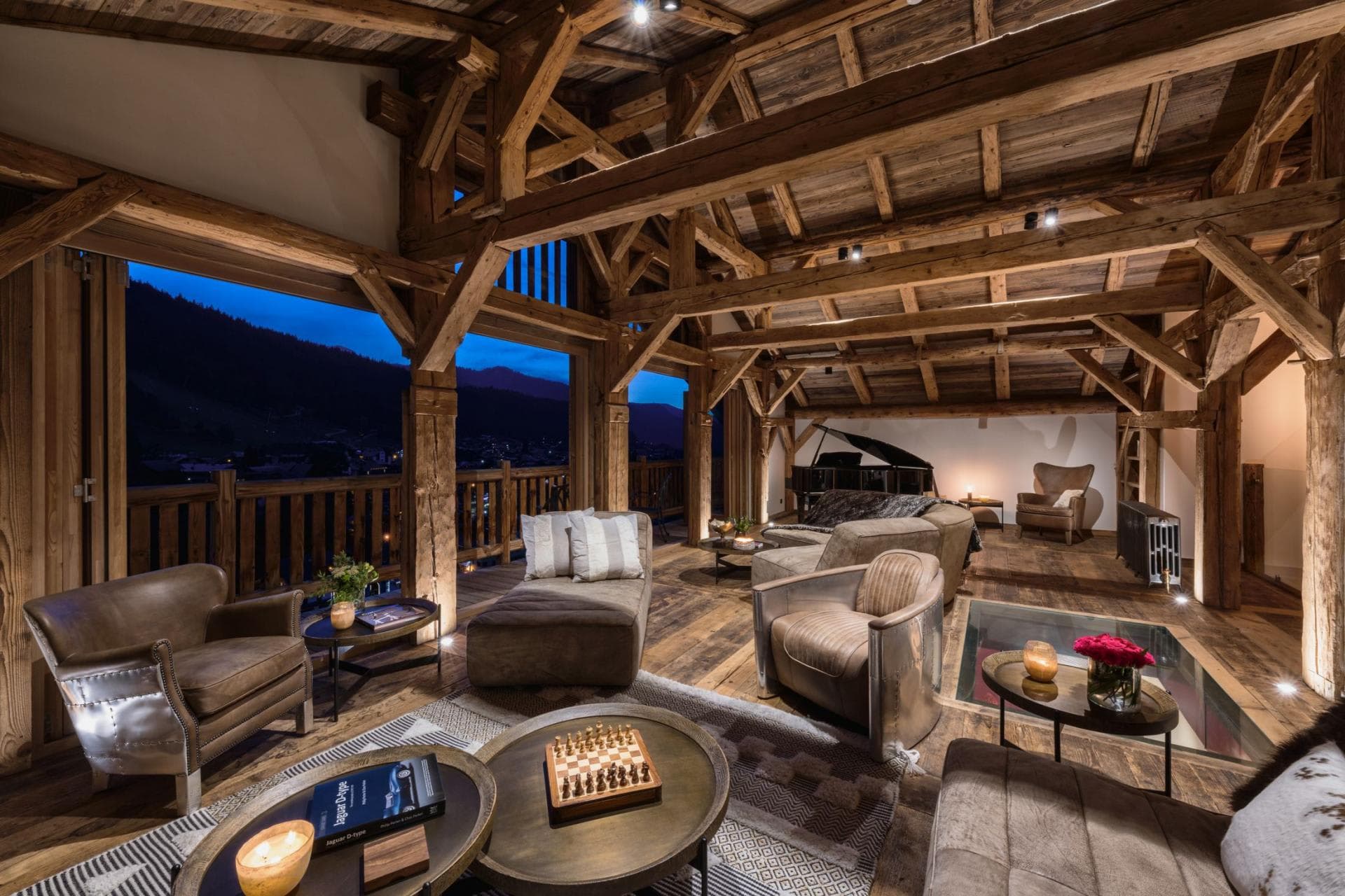 Loft lounge with exposed timber beams, grand piano, and valley views