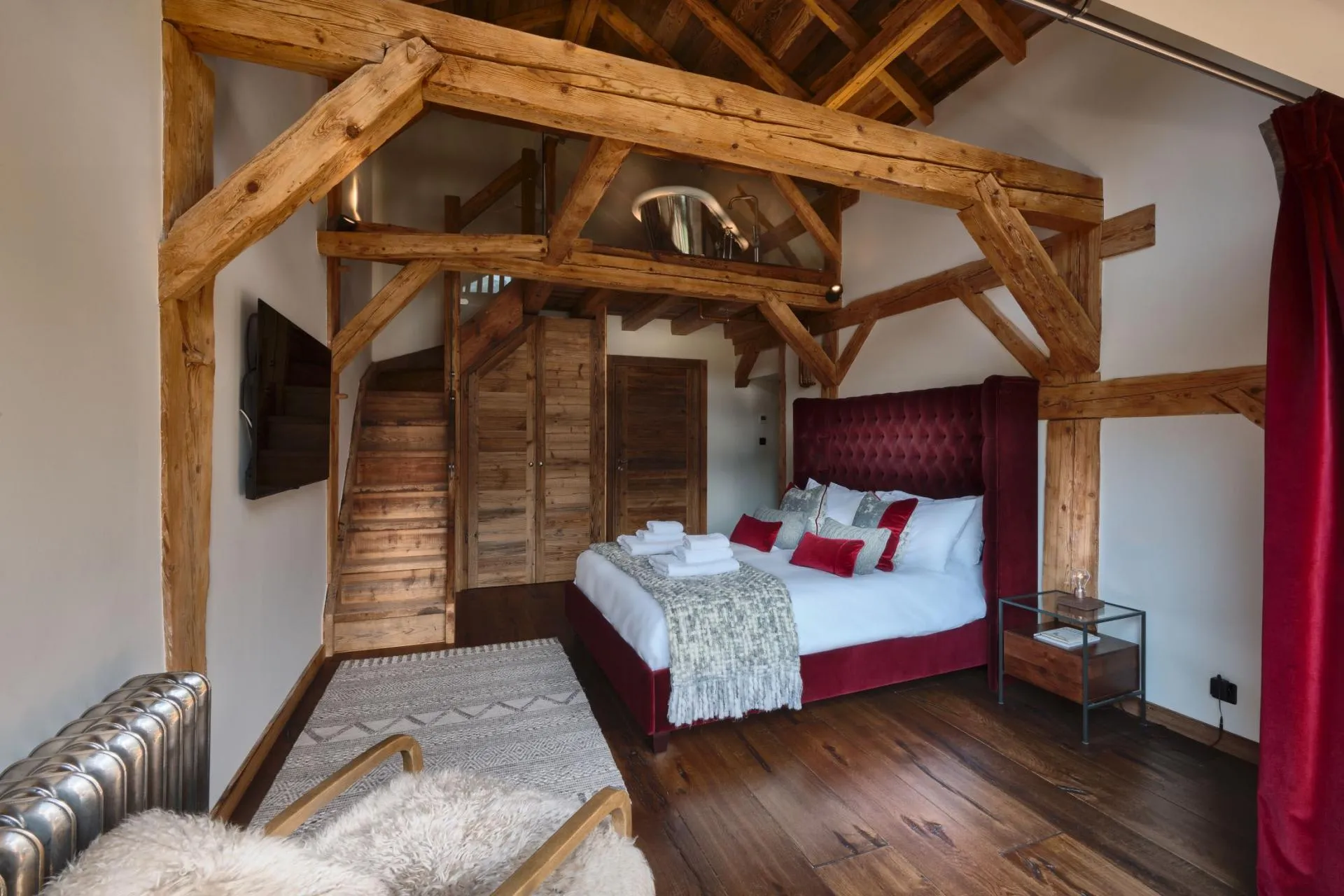 Burgundy king bedroom with a mezzanine roll-top bath above