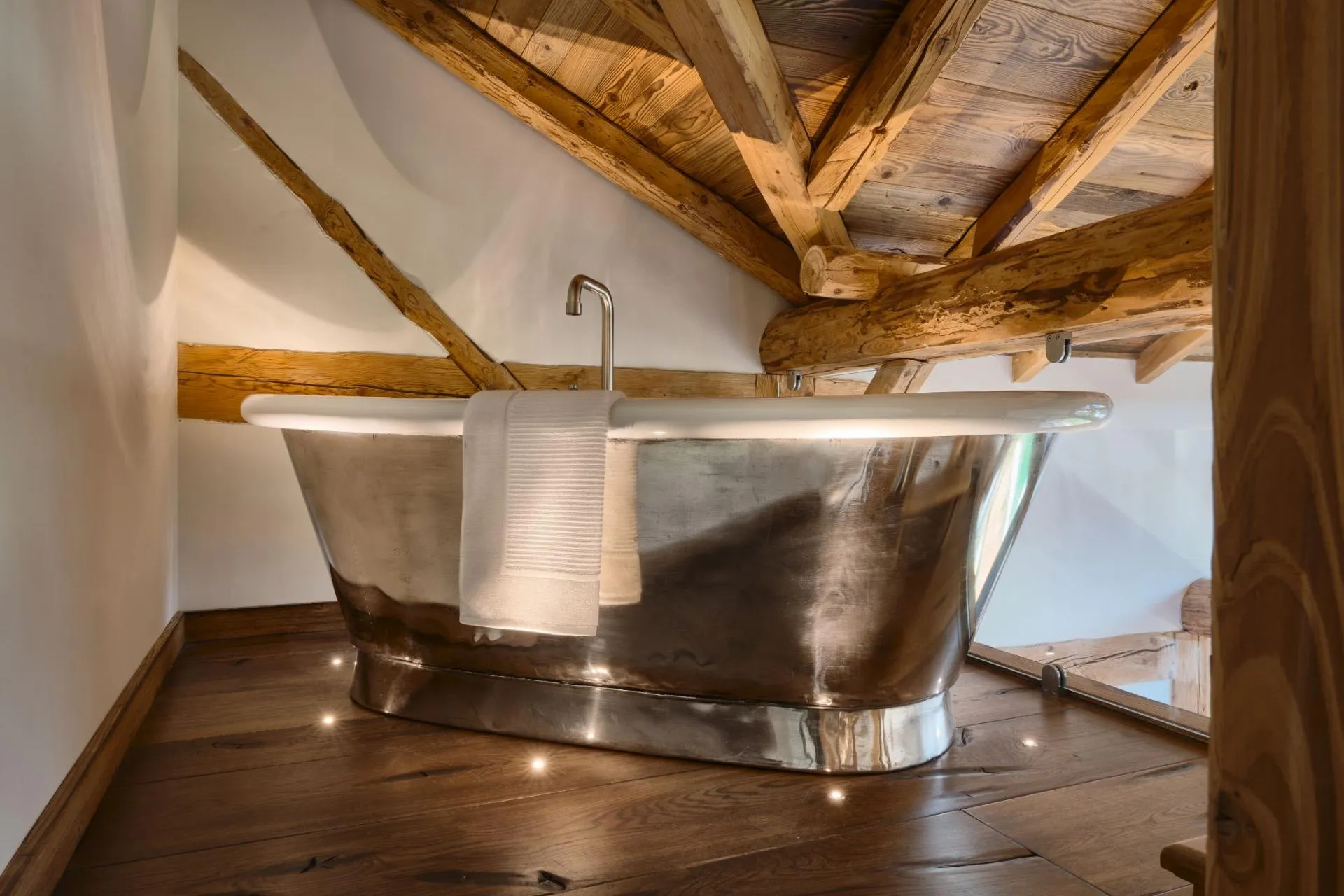 Mezzanine bathroom with a freestanding roll-top bath and timber beams