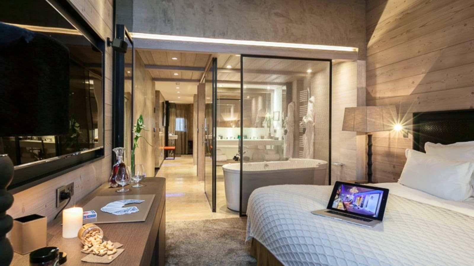 Bedroom featuring glass-walled en-suite bathroom with soaking tub