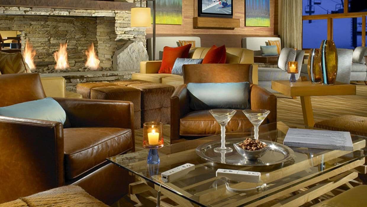 Lounge with leather armchairs, stone fireplace, and ski-in/ski-out views