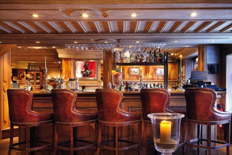 Traditional wood bar with leather seating for five and backlit shelving