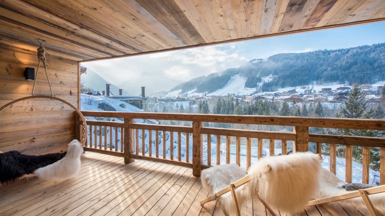 Covered balcony with hanging swing chair and ski slope views