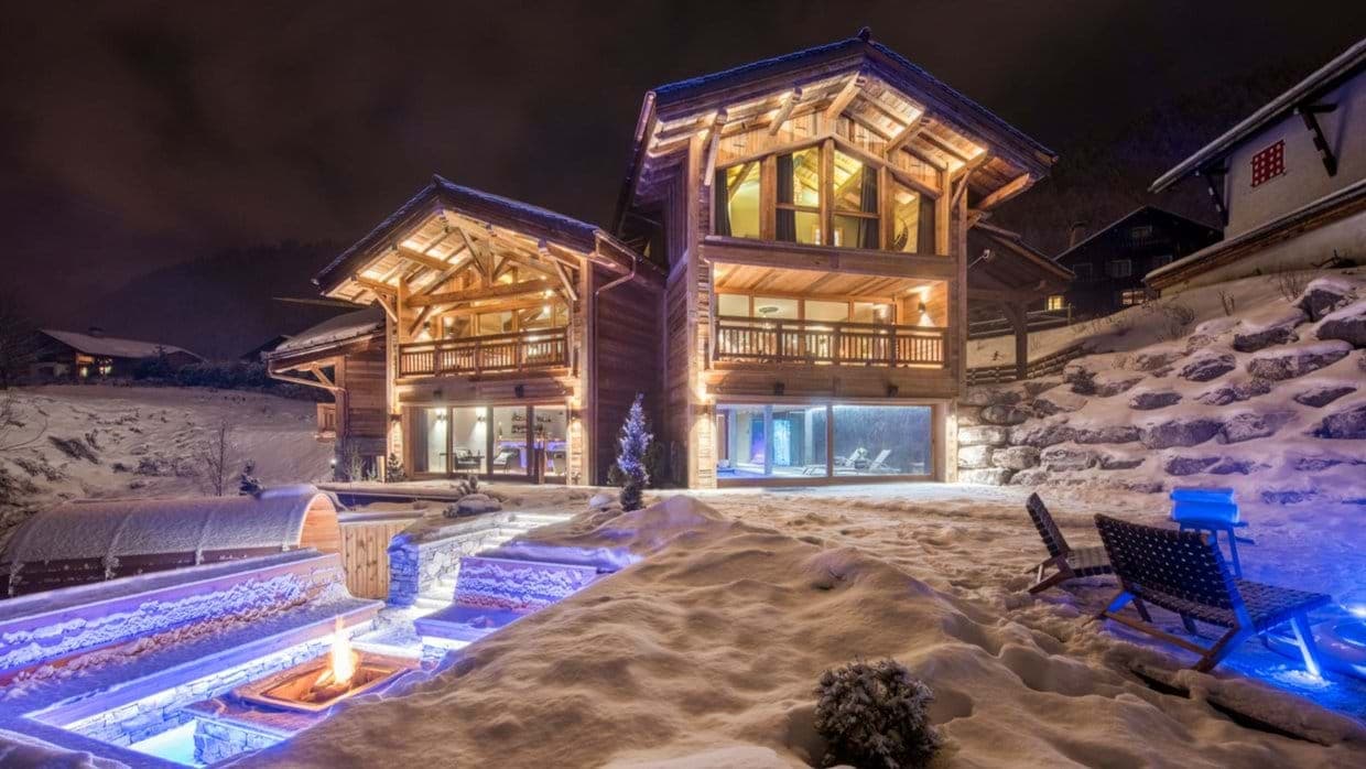Chalet exterior with outdoor fire pit, barrel sauna, and indoor pool