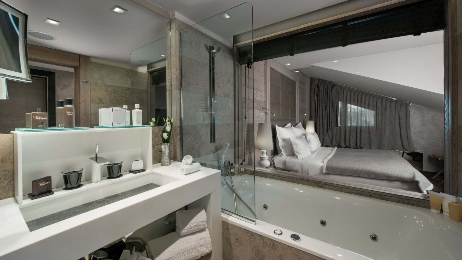 Jetted bathtub with glass partition overlooking the primary bedroom