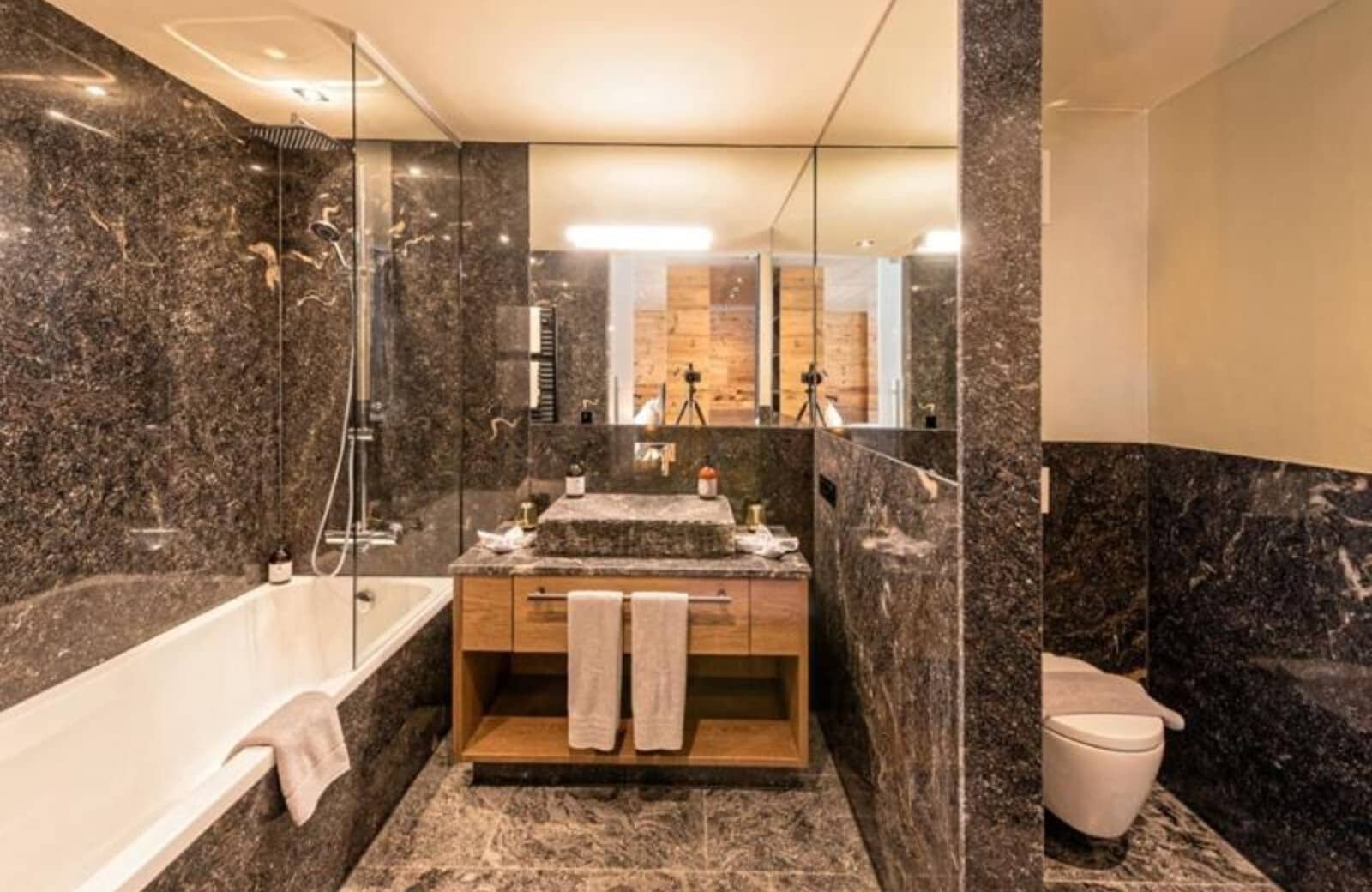 Dark marble bathroom with rainfall showerhead and stone vessel sink
