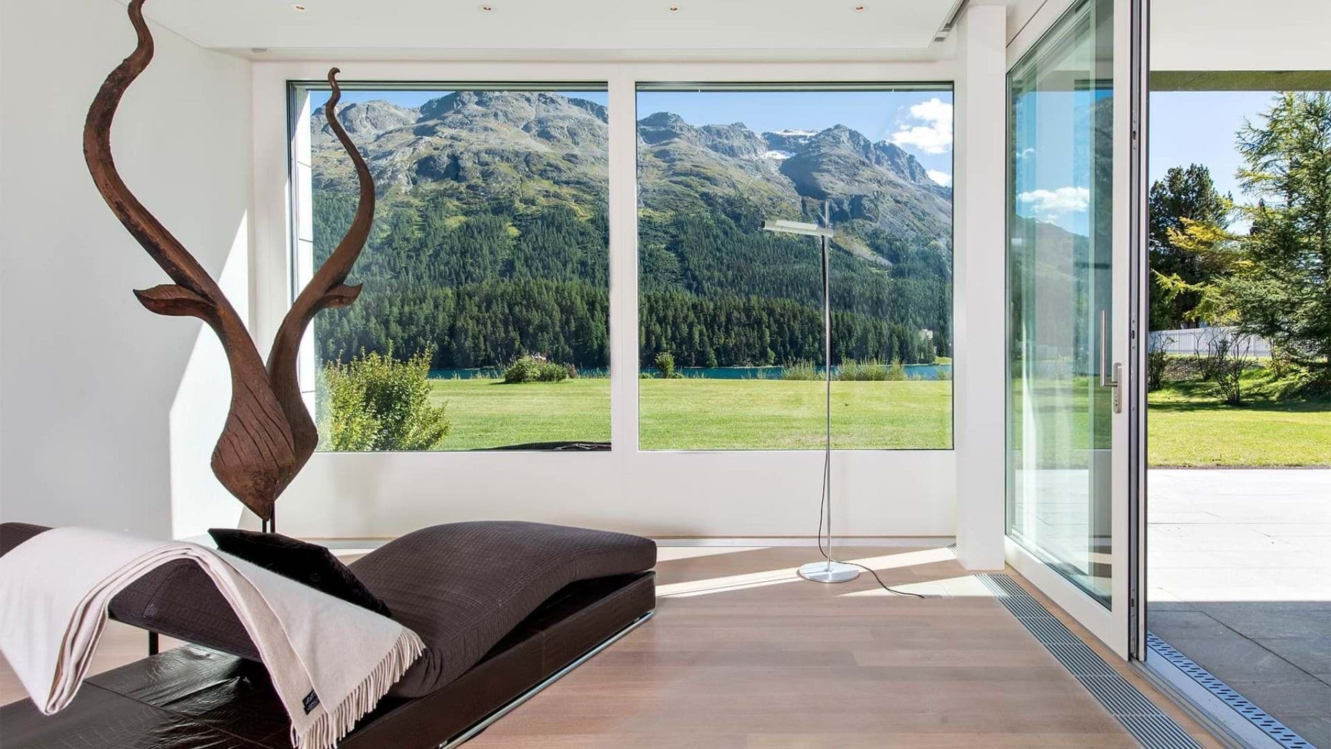 Lounge area with chaise and floor-to-ceiling mountain and lake views