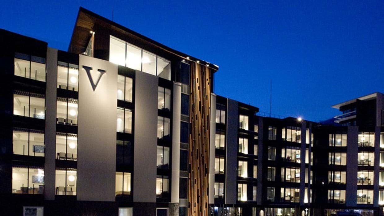 Building exterior at dusk with floor-to-ceiling windows and private balconies