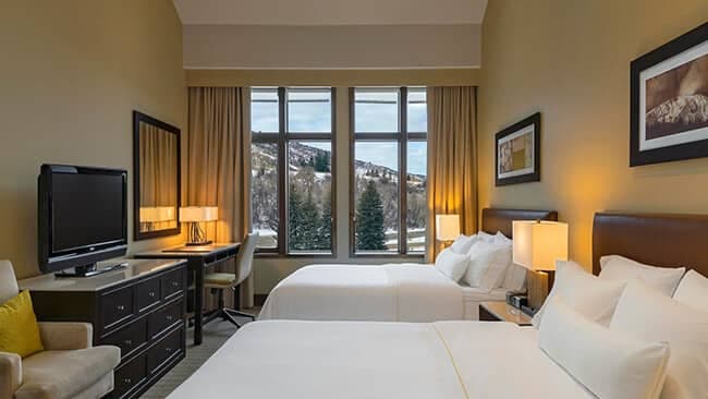 Guest bedroom with two queen beds, desk, and mountain views