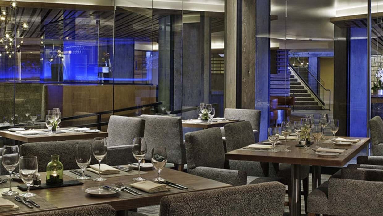 Dining area with full-service table settings and glass-walled wine cellar