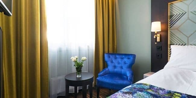 Guest bedroom with blackout curtains and velvet armchair seating