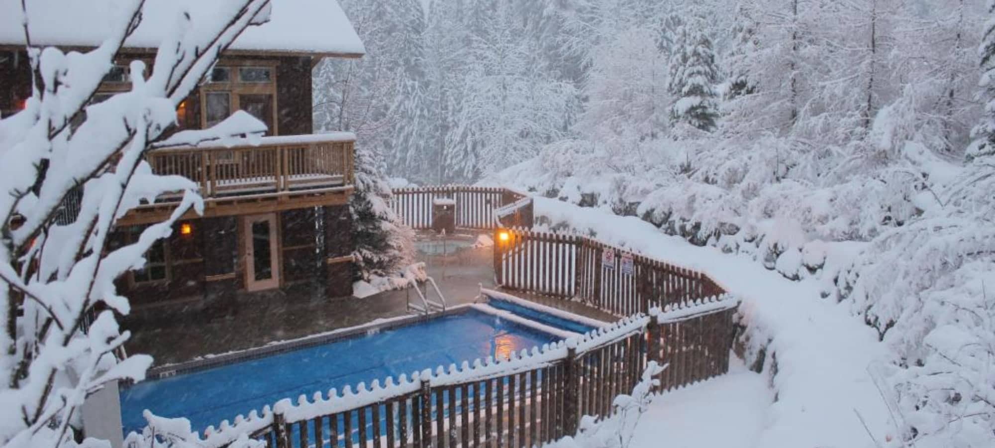 Fenced outdoor pool area with separate hot tub and forest views