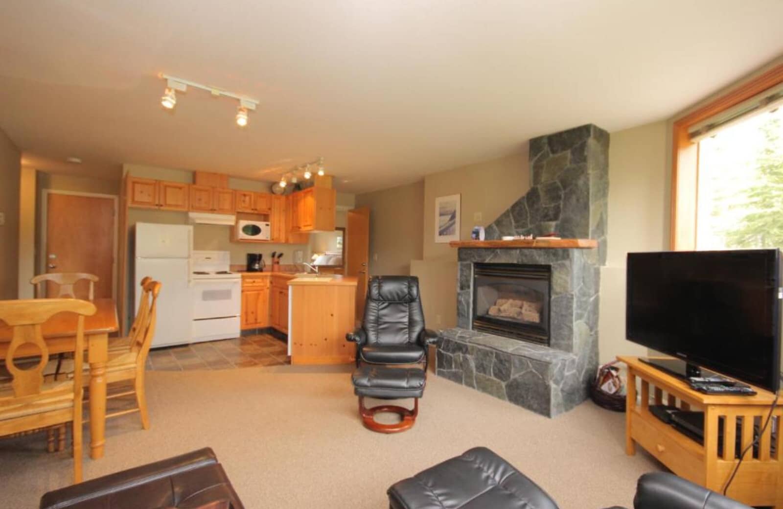 Open-plan living area featuring stone gas fireplace and full kitchen