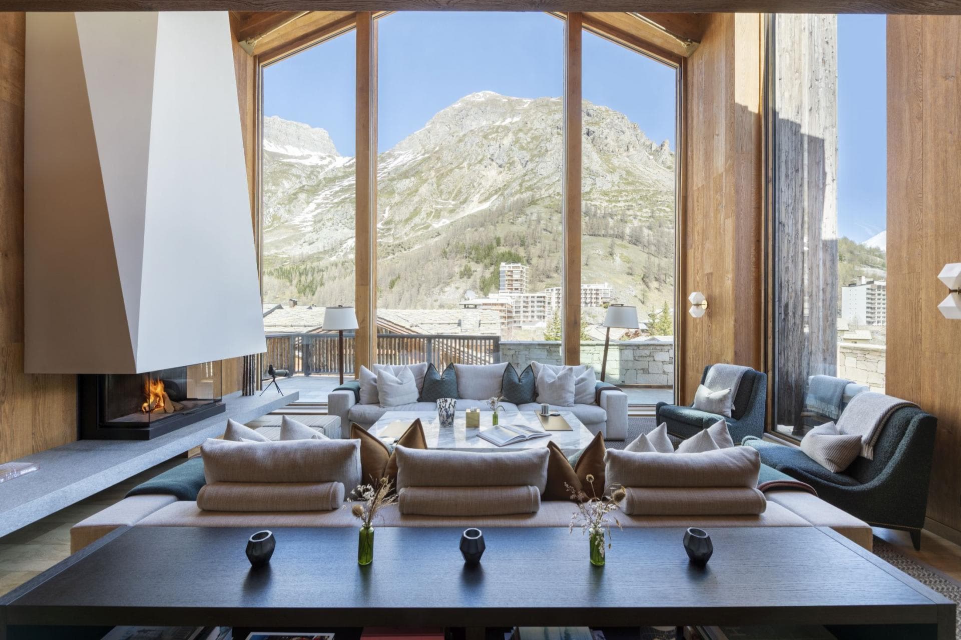 Living room with wood-burning fireplace and floor-to-ceiling mountain views