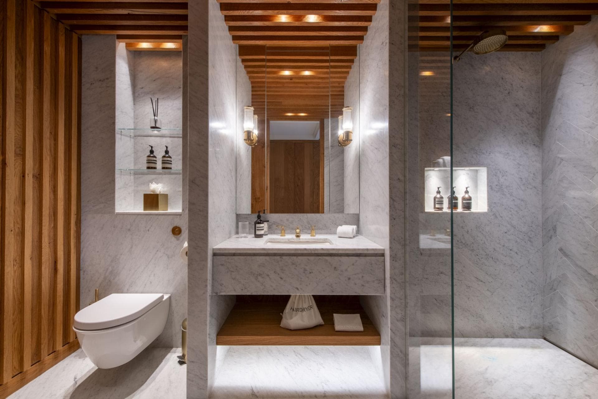Bathroom with marble surfaces, walk-in shower, and wood-slat ceiling