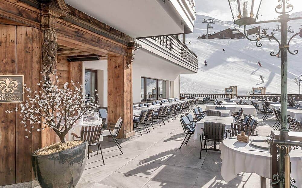 Ski-in/ski-out outdoor terrace with dining tables and mountain views