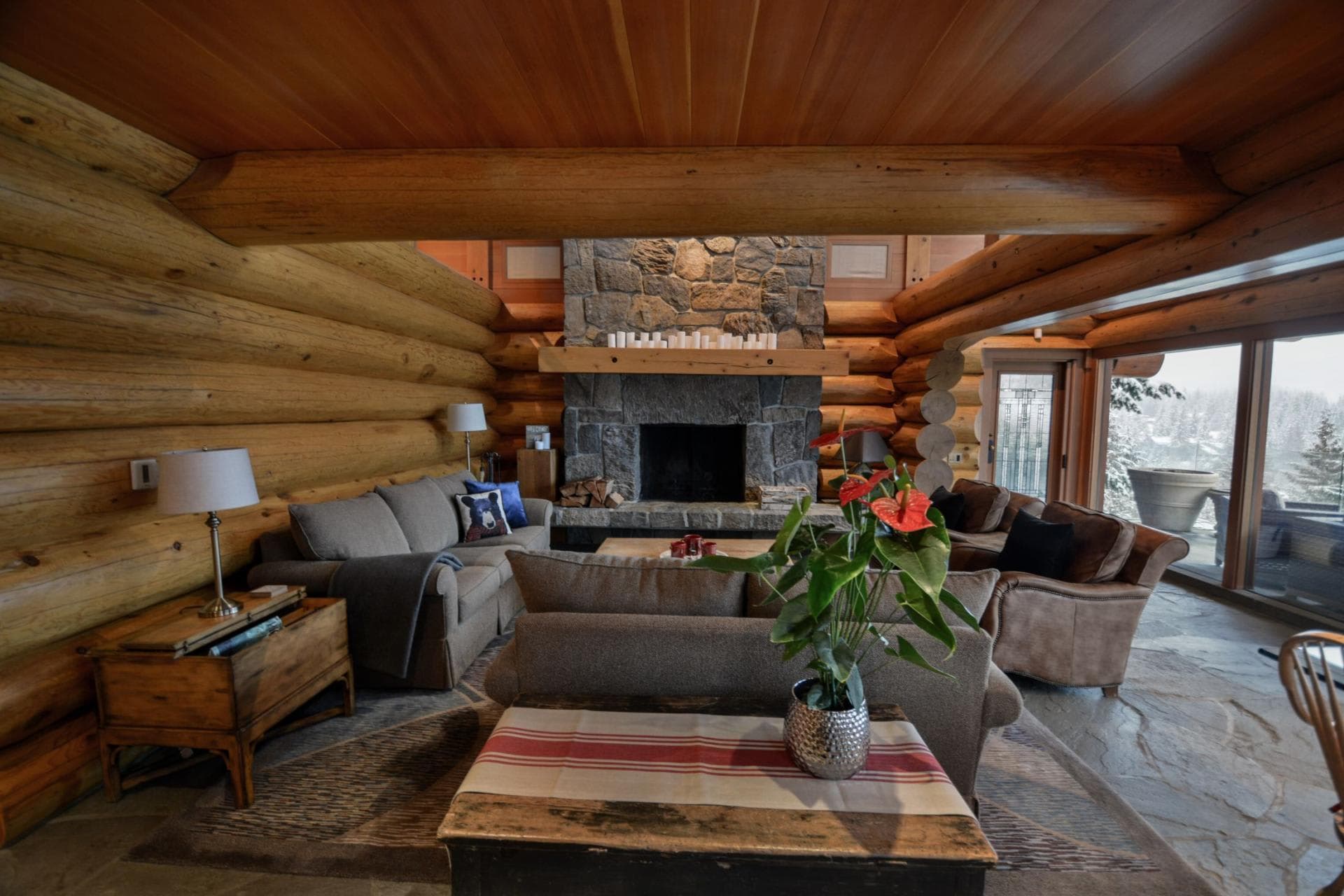 Log cabin living room with stone fireplace and flagstone flooring