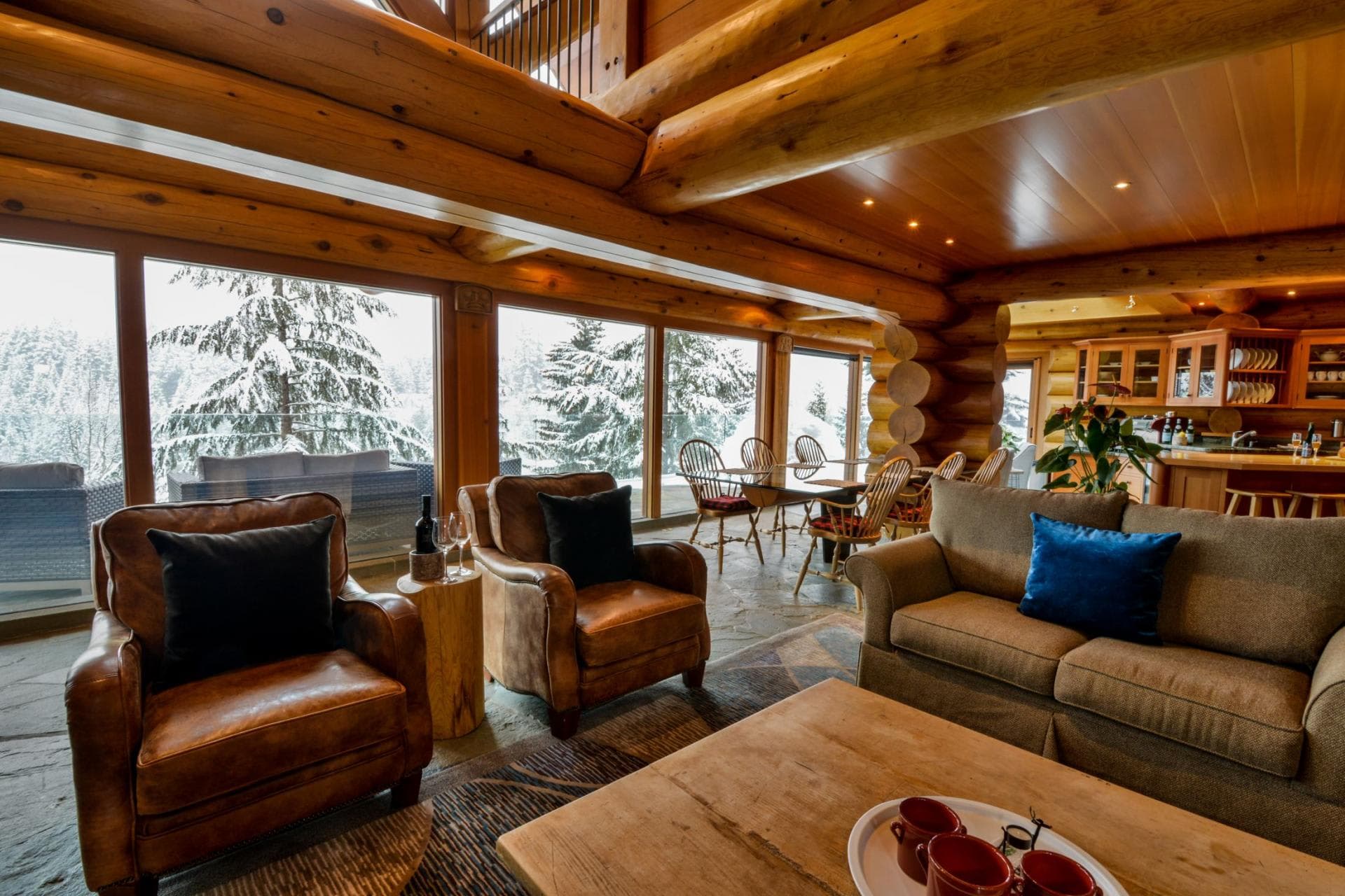 Open-plan living area with stone floors and floor-to-ceiling forest views
