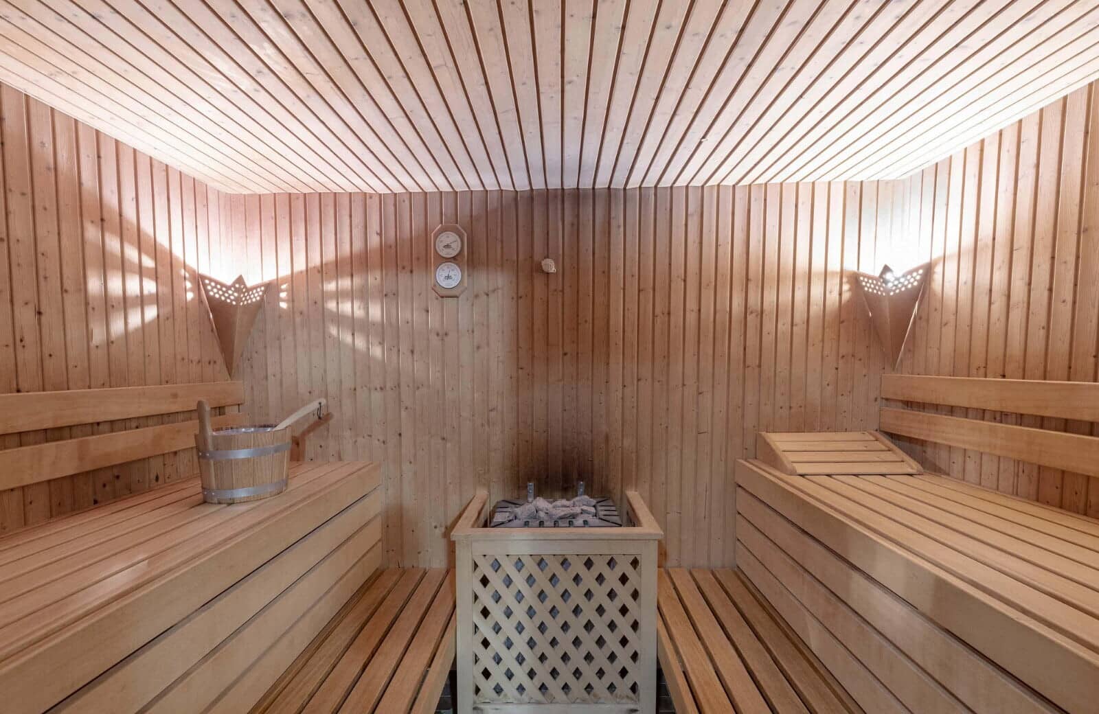 Wood-paneled sauna with tiered seating and electric rock heater