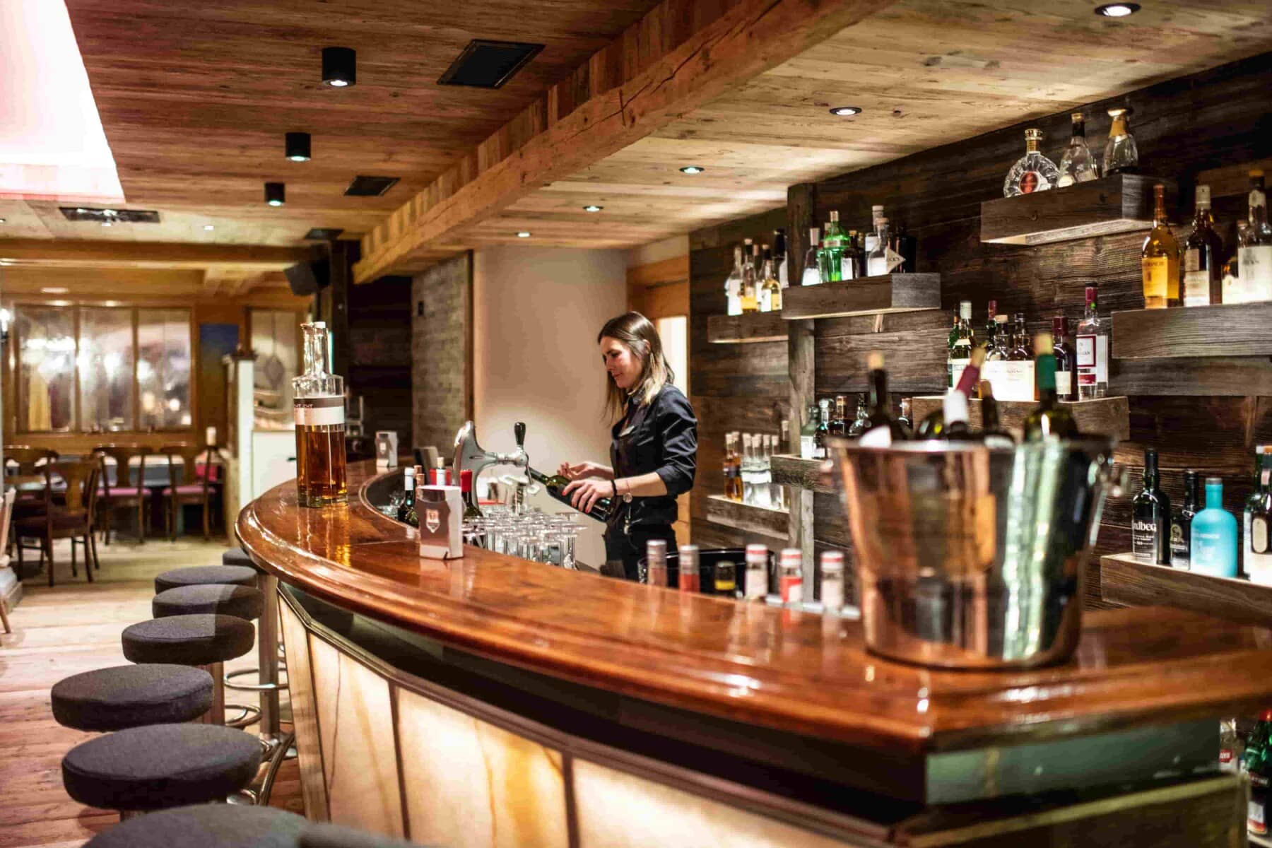 Private cocktail bar with curved seating and reclaimed wood finishes