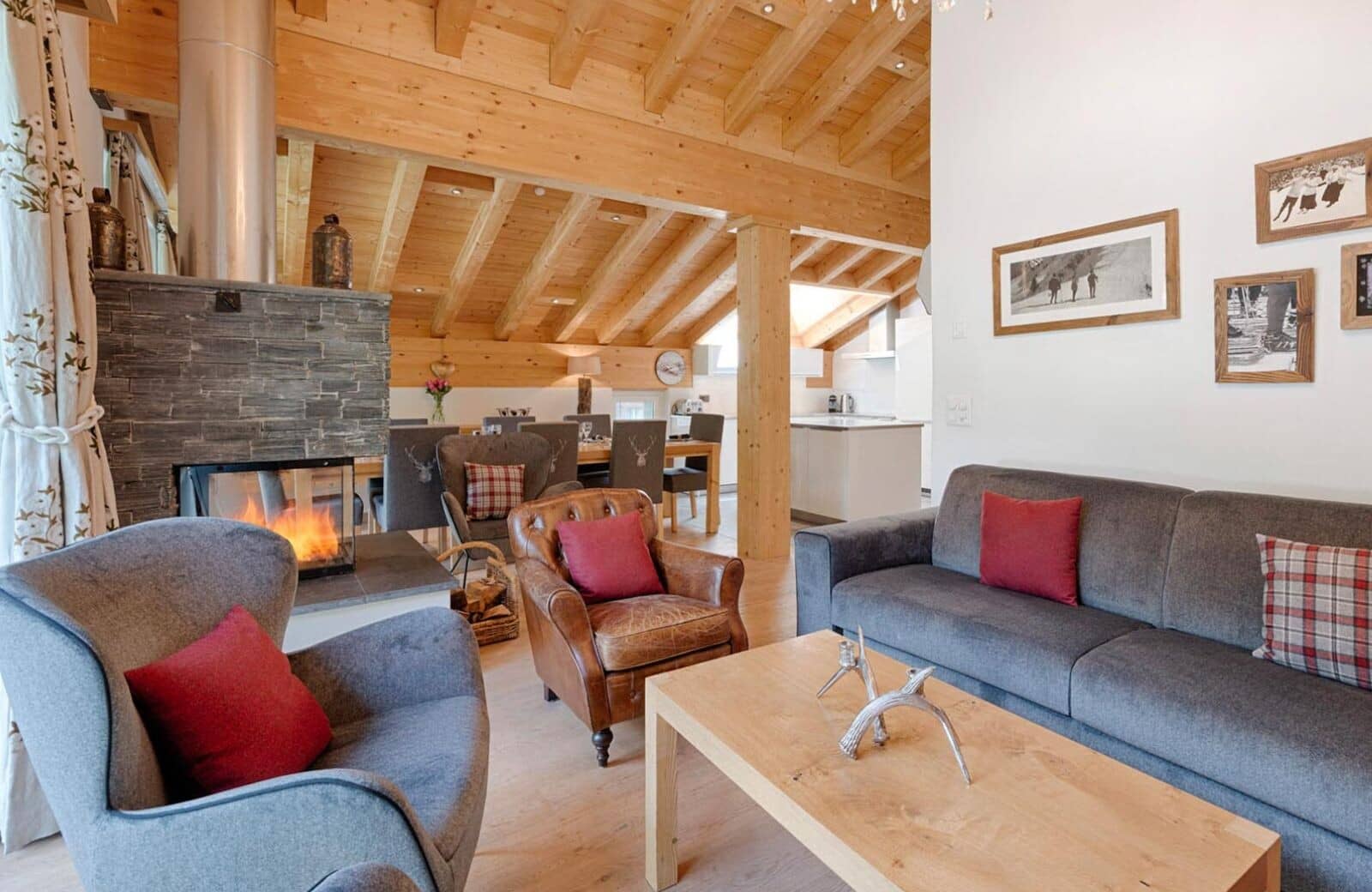 Open-plan living area featuring three-sided glass fireplace and vaulted timber ceilings